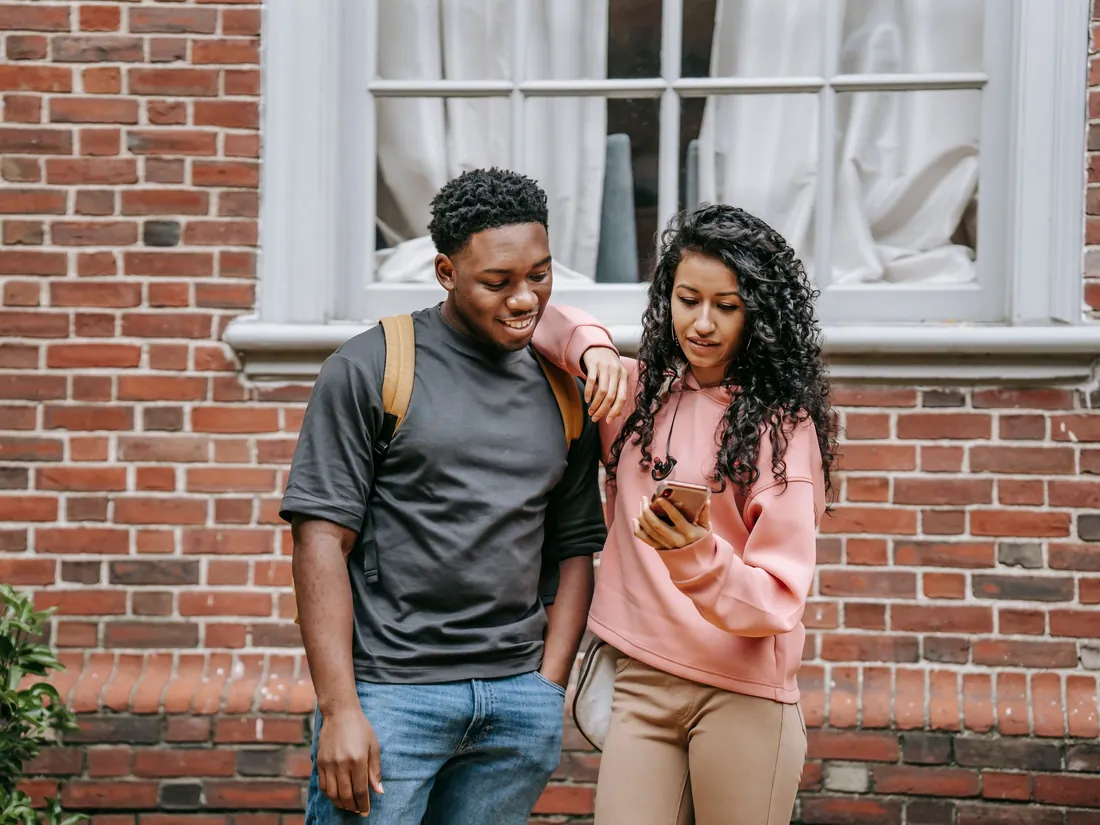 Two friends smiling at a video on a phone